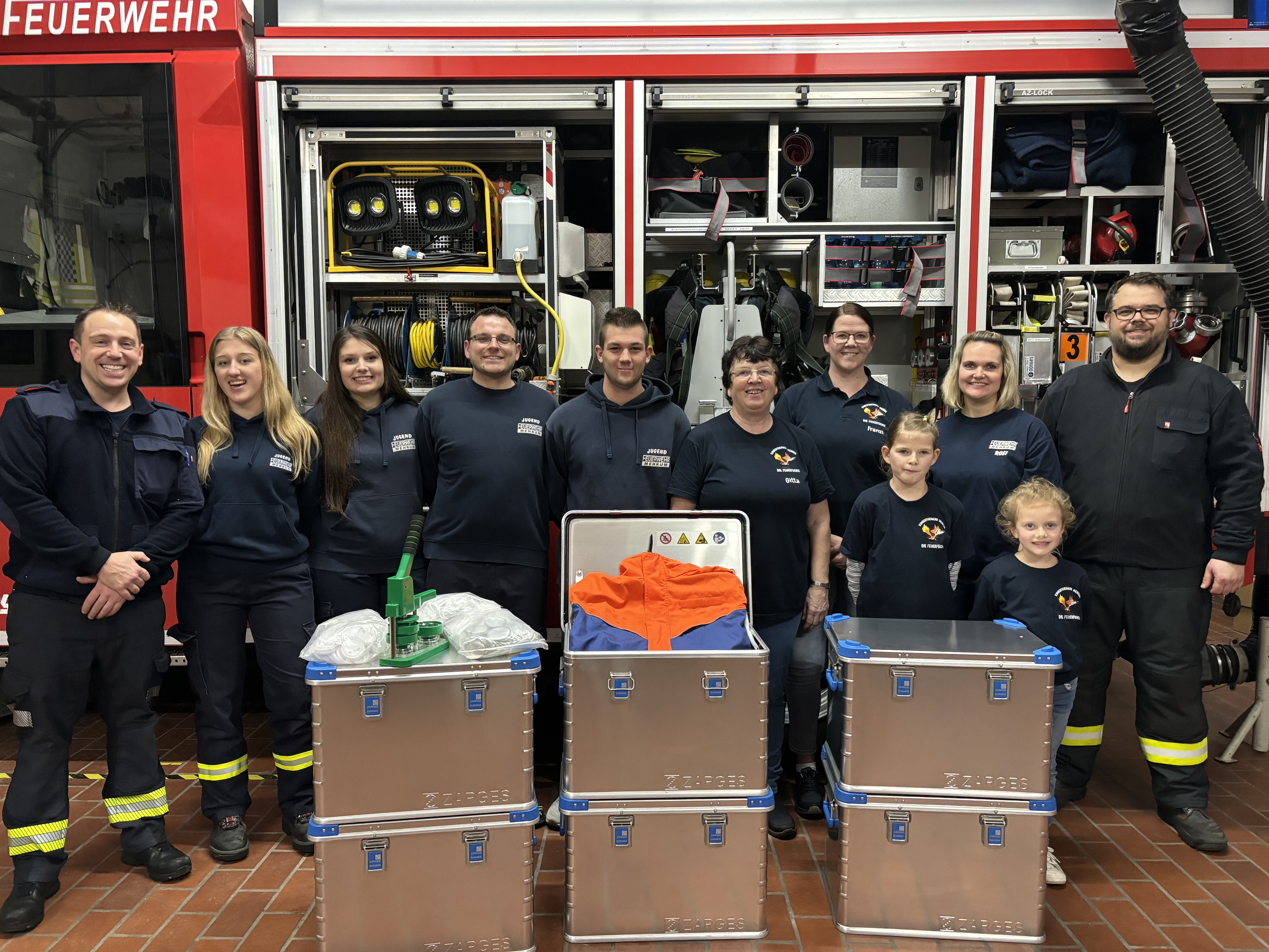 Ortsbrandmeister Schulte und Stellvertretender Ortsbrandmeister Brathering freuen sich mit dem Team von der Jugendfeuerwehr und Kinderfeuerwehr über neue Gerätschaften.